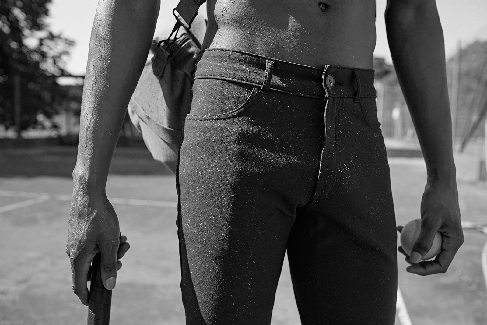Black-and-white close-up of a man in åäö’s Blue Black Pants with water droplets, highlighting the water-repellent fabric.