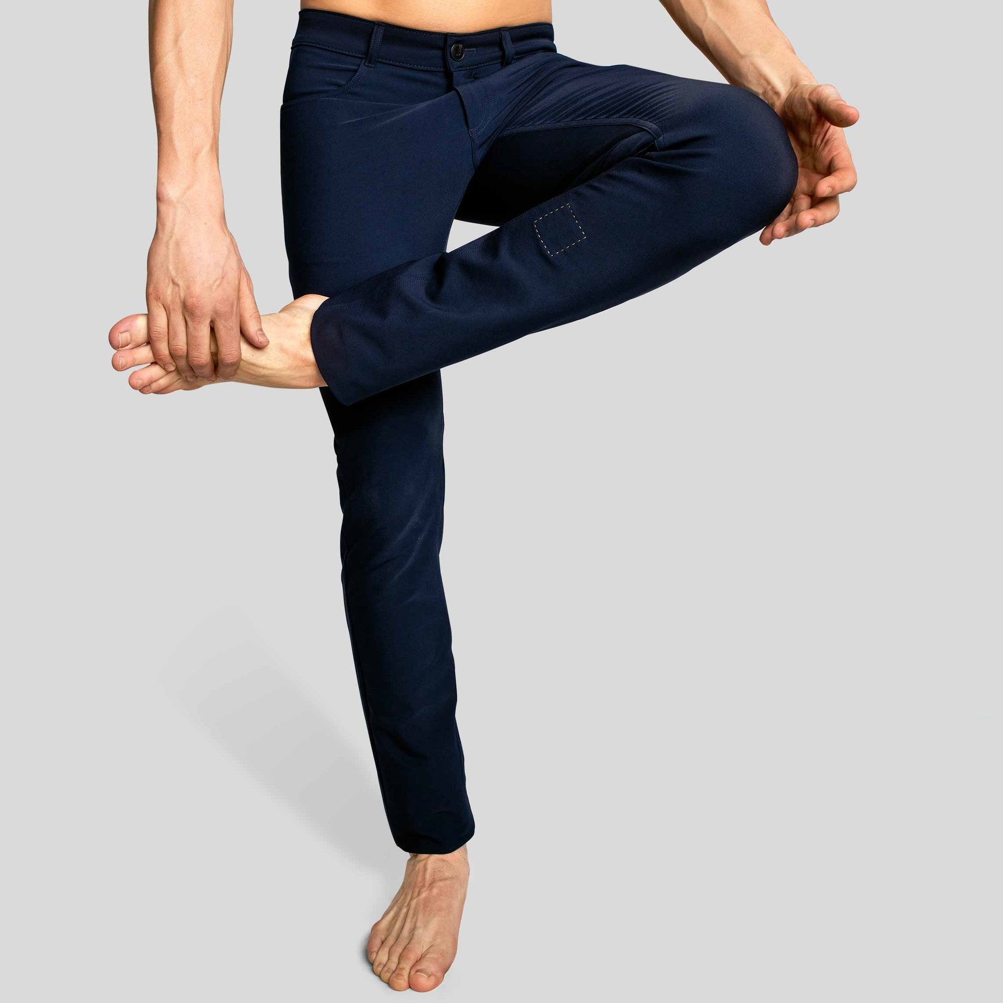 Front view of a man in The Pants by åäö in Blue Black, with one leg crossed, showing their tailored fit and flexible design.