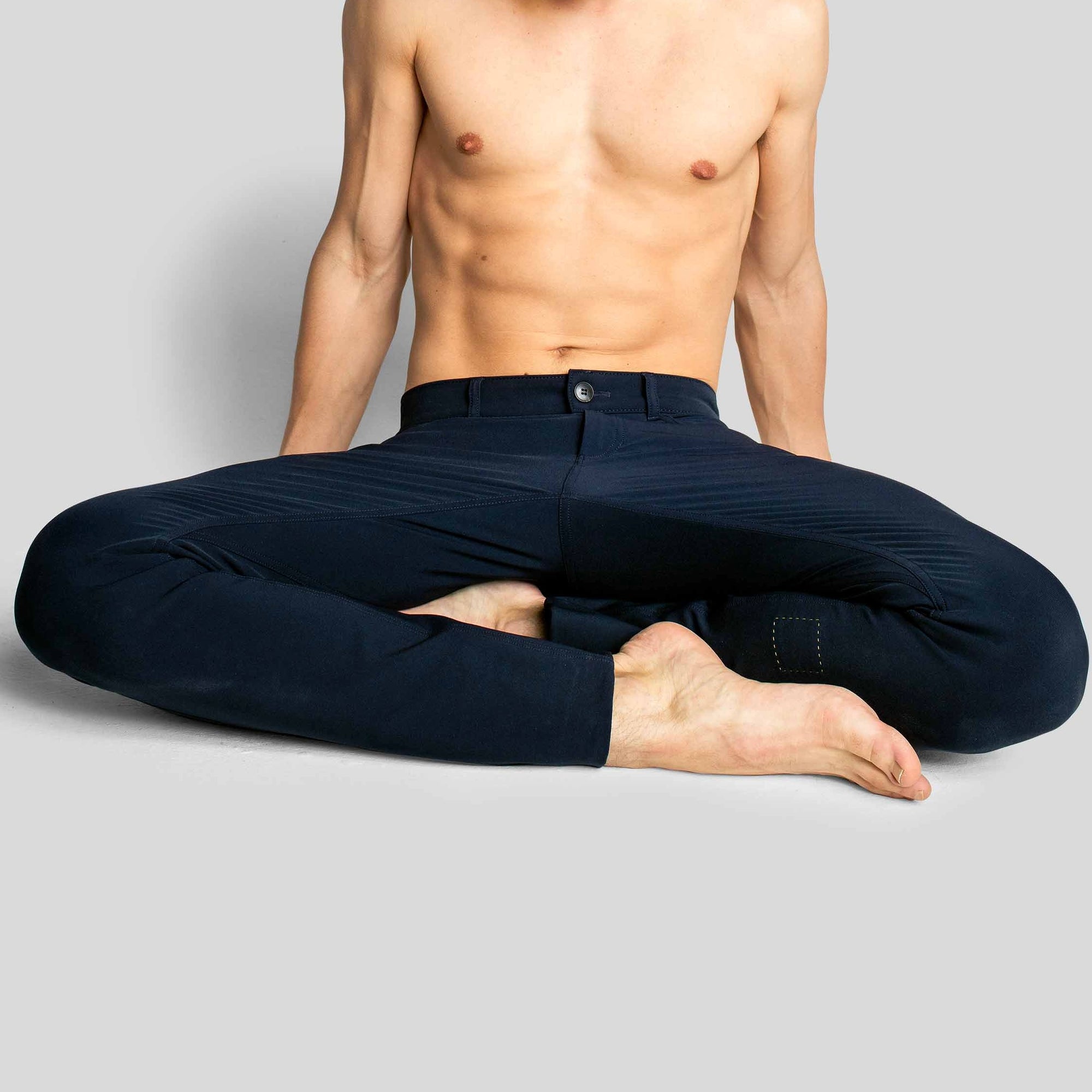 A man sitting with his legs crossed, wearing The Pants by åäö in Blue Black, showcasing their comfortable fit and design.