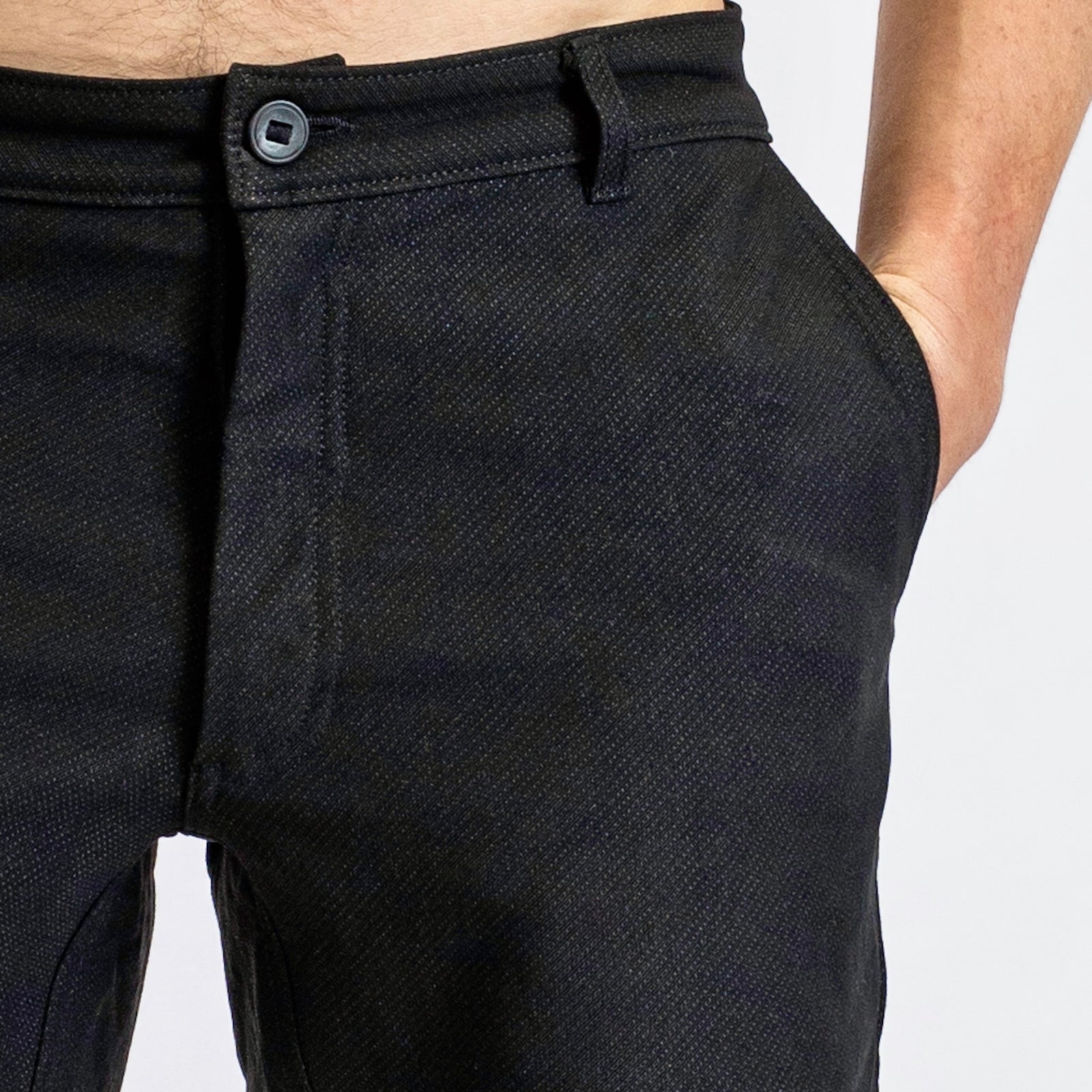 Close-up of a man in åäö’s Forever Pants, hand in pocket, highlighting the Dyneema fabric texture and a reinforced button.