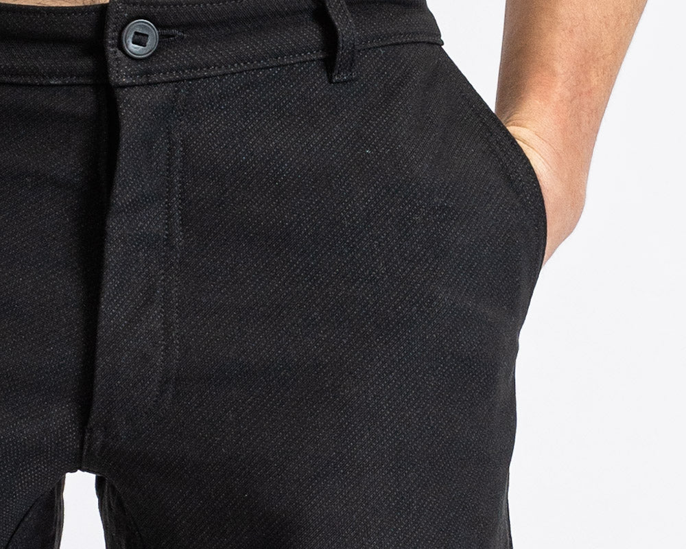 Close-up of a man in åäö’s Forever Pants, hand in pocket, highlighting the Dyneema fabric texture and a reinforced button.