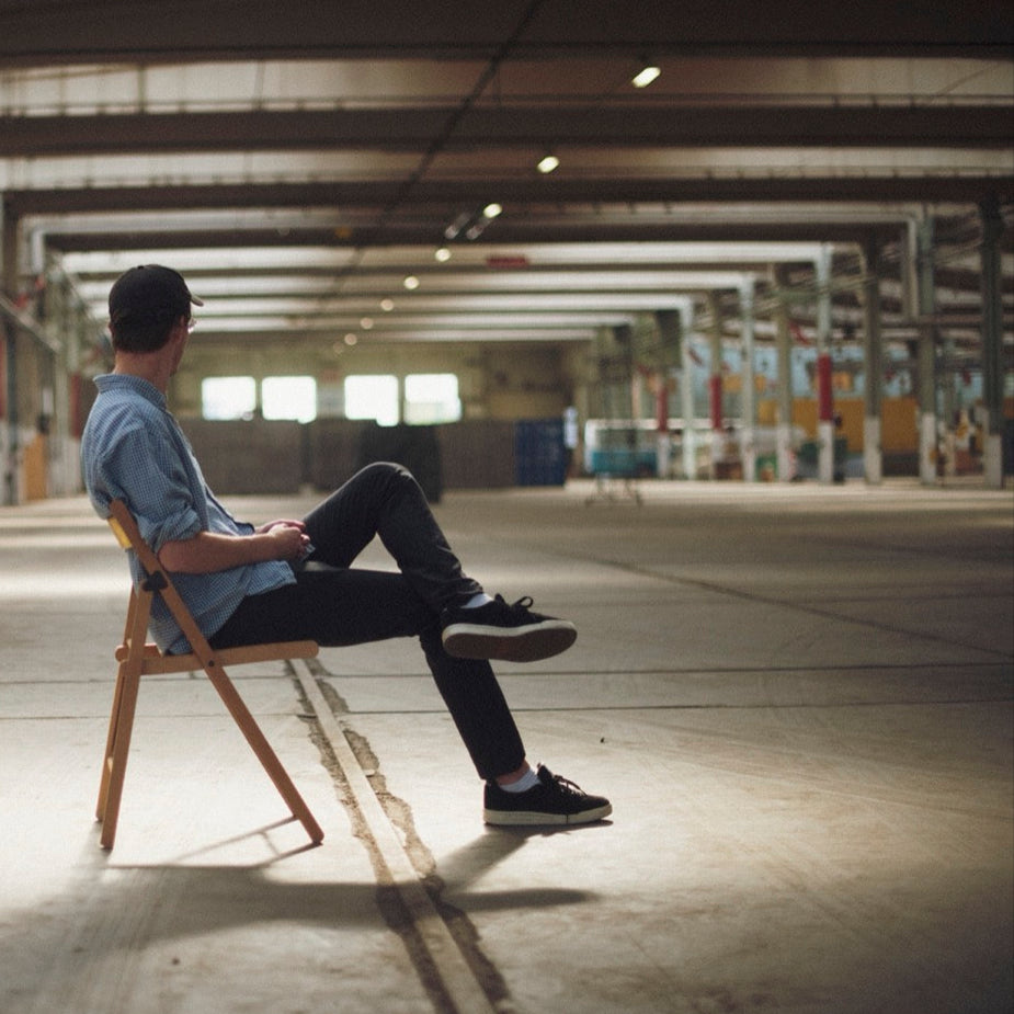 Person sitting on a chair next to a yellow ball in an industrial setting