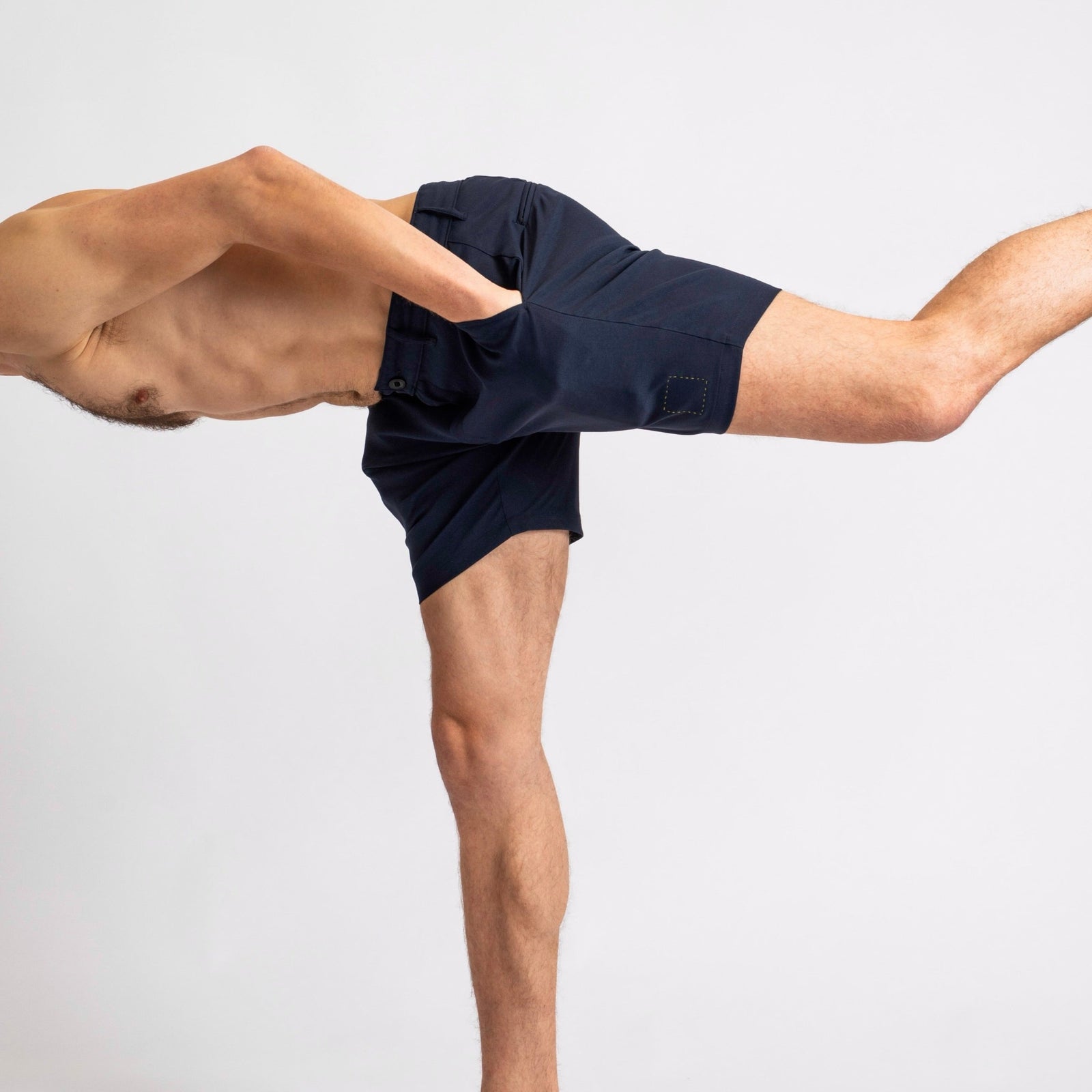 A man standing on one leg in The Shorts by åäö in Deep Blue, highlighting their comfortable fit and timeless design.