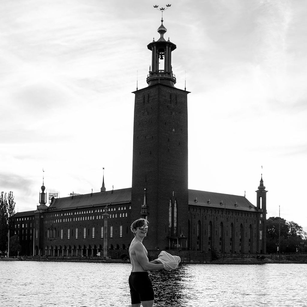 A man wearing The Shorts by åäö in Deep Blue, with Stockholm City Hall in the background.