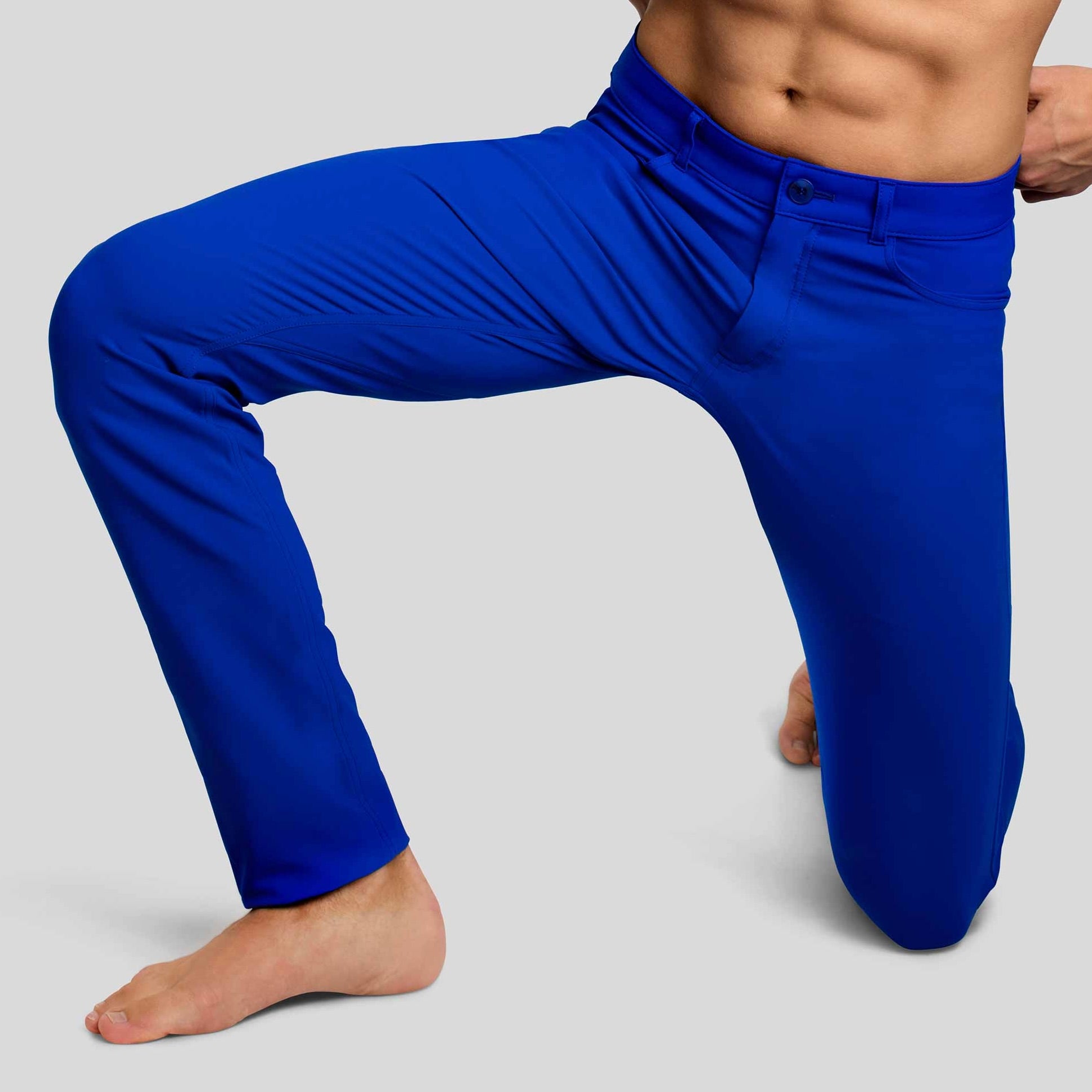 Front view of a man in The Pants by åäö in Brilliant Blue, in a one-knee position, showcasing their comfort and movement.