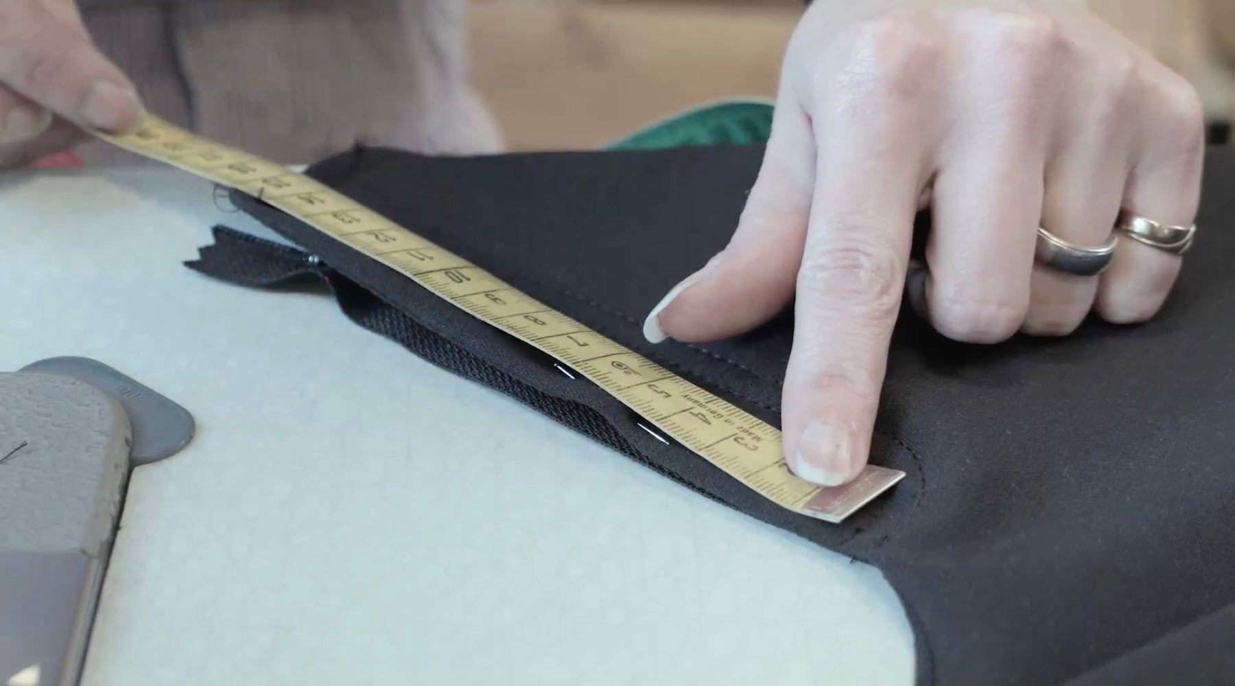 A seamstress measuring the fabric for åäö’s The Pants, highlighting meticulous craftsmanship and attention to detail.