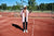 A man standing on a tennis court in The Pants by åäö in Tech Black, throwing a tennis ball, showcasing their versatile design.