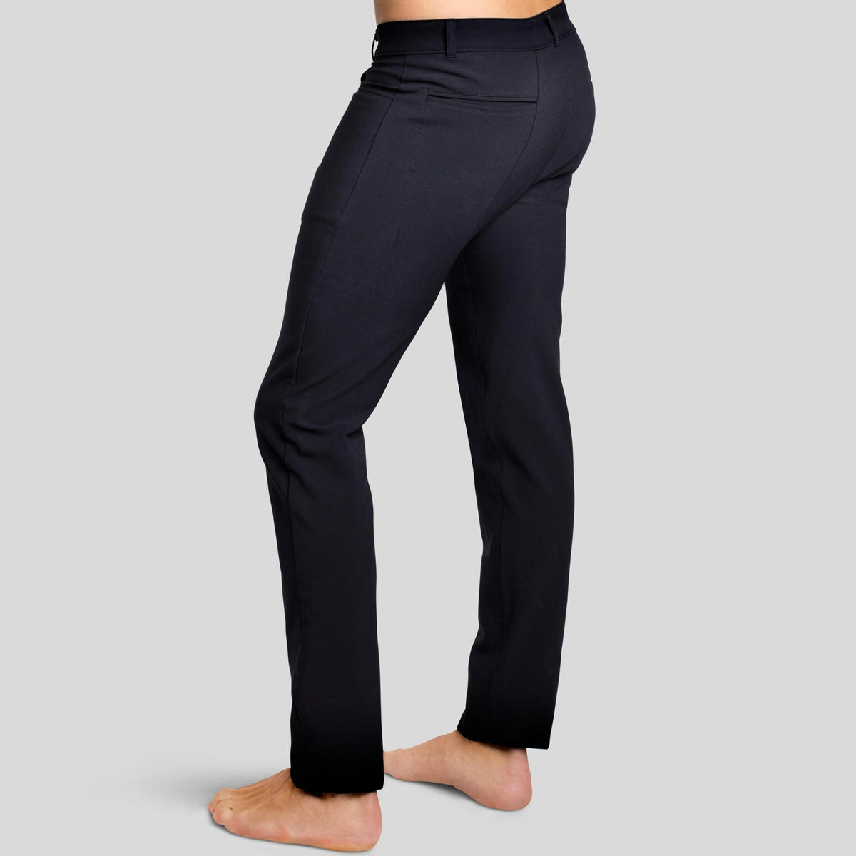 Side-back view of a man in The Pants by åäö in Tech Black, highlighting the double-piped back pockets and tailored fit.